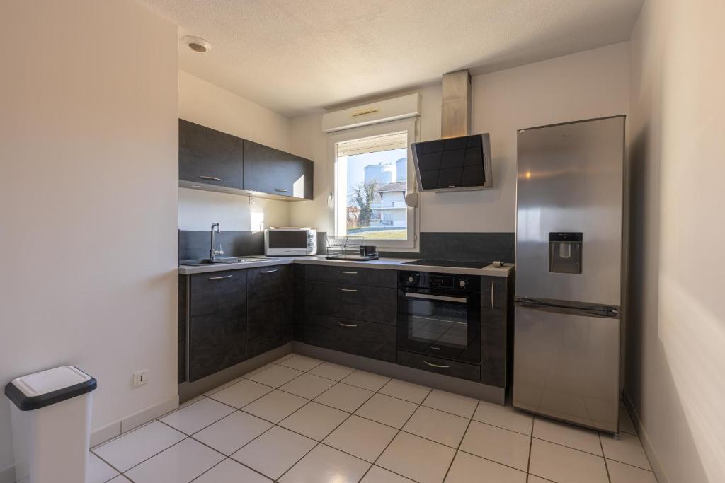 a kitchen with black cabinets and a stainless steel refrigerator at LaConciergerieJonzac, Appartement La Désirade in Jonzac