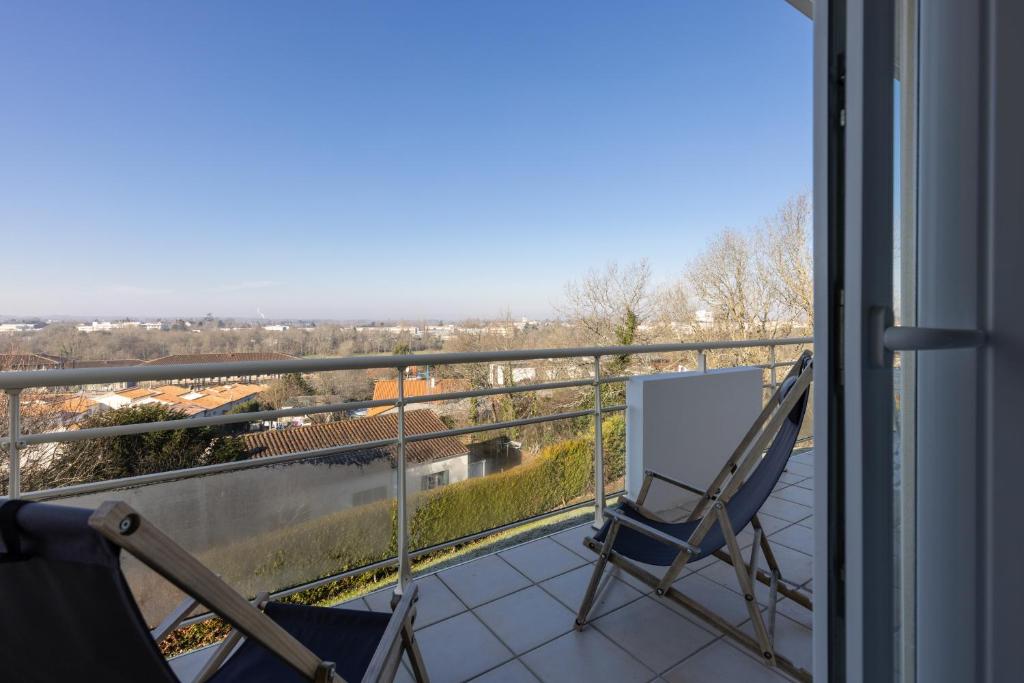 a balcony with chairs and a view of a city at LaConciergerieJonzac, Appartement La Désirade in Jonzac