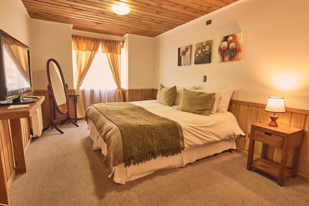 Un dormitorio con una cama grande y un televisor. en Hotel y Cabañas Borde Andino, en Las Trancas