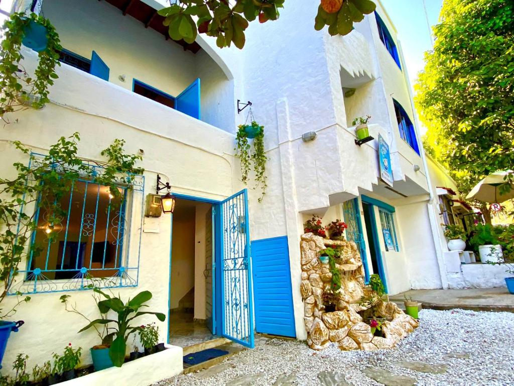 a white building with blue doors and plants at Cabaña Nro 80 El Portón de La Aldea in Doradal