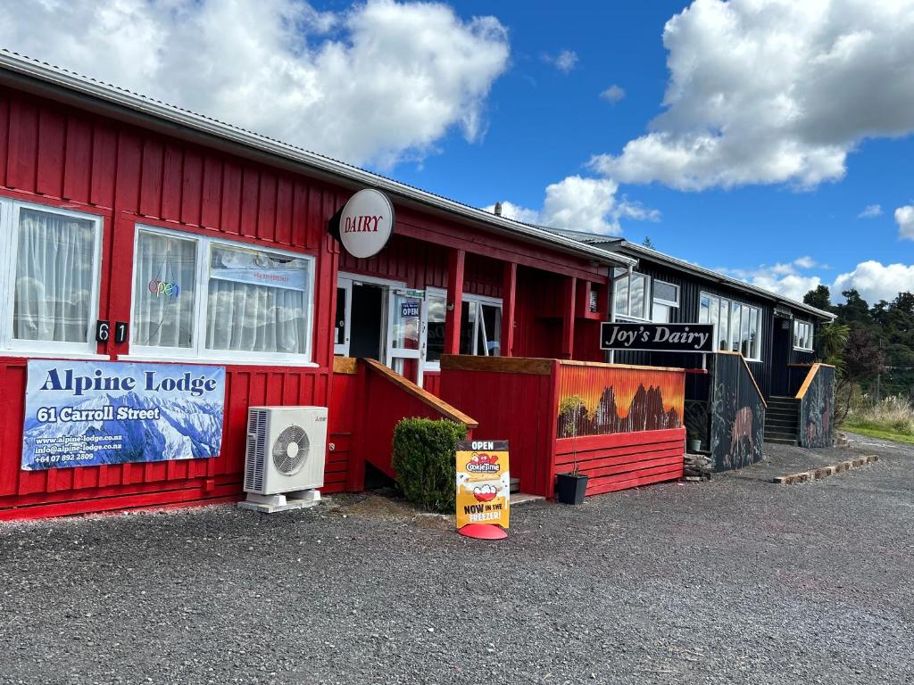 a red building with a sign on the side of it at National Park Alpine Lodge in National Park