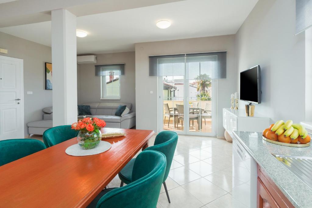 a kitchen and living room with a wooden table and green chairs at Marisol Premium - fußläufig zum Meer in Funtana