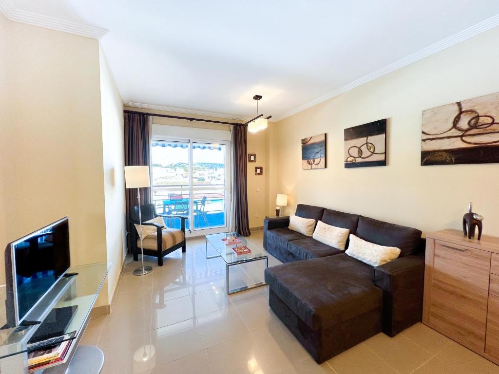 uma sala de estar com um sofá e uma televisão em Apartamento acogedor de 2 dormitorios a solo 150 m de la playa Sabinillas, Manilva em San Luis de Sabinillas