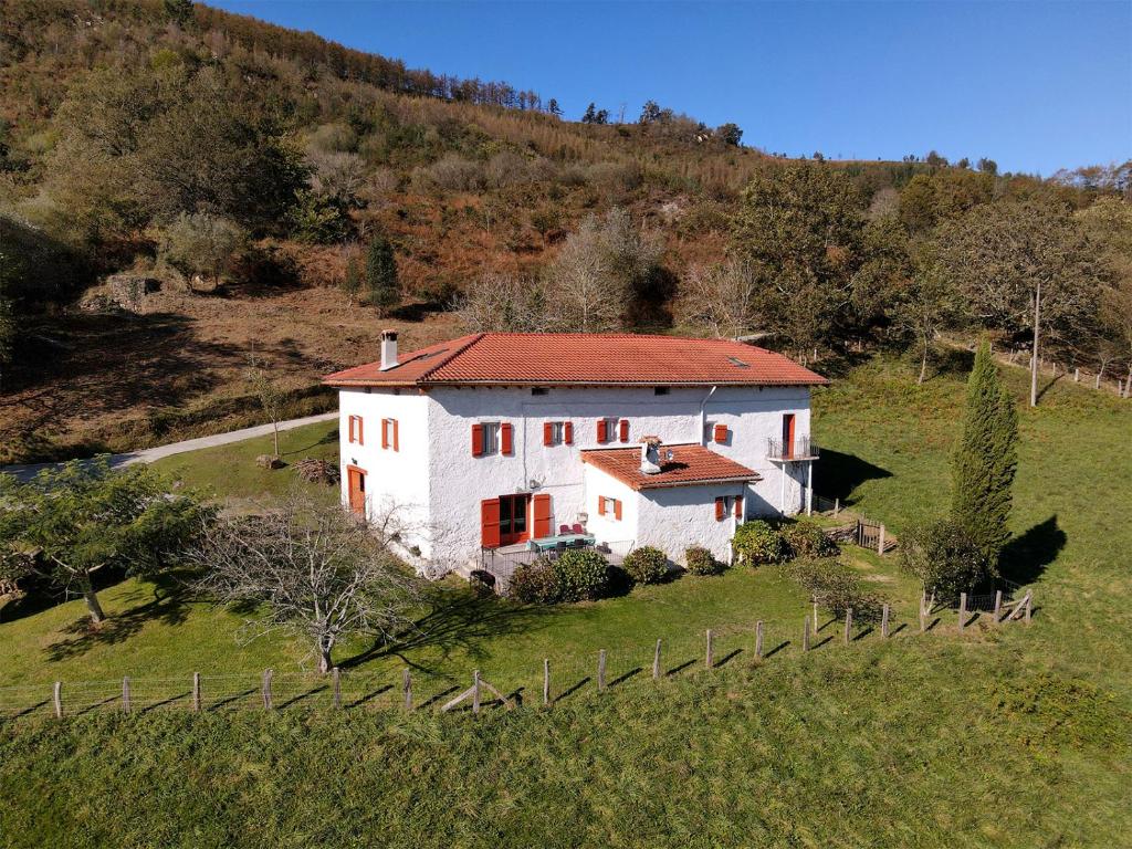 a white house with a red roof in a field at Casa Rural Erreteneko borda in Vera de Bidasoa