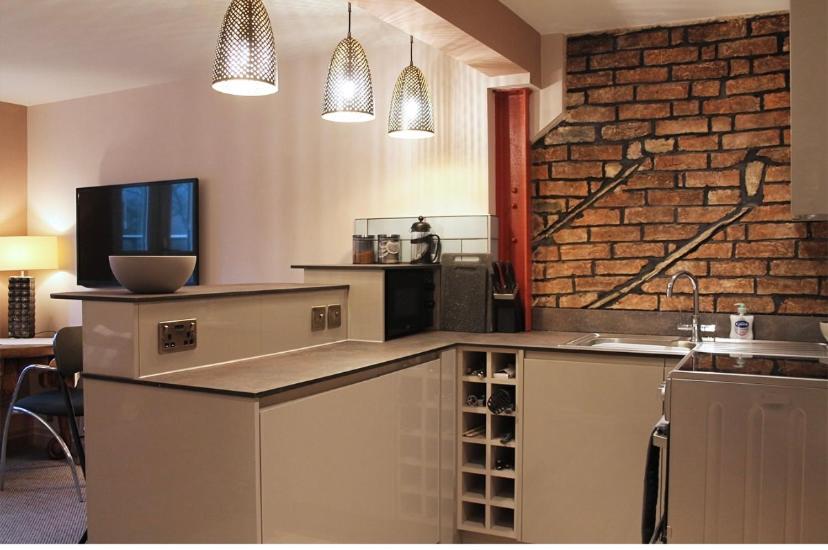 una cucina con bancone e muro di mattoni di Wharmton luxury apartment a Dobcross