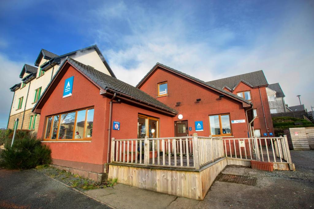 una casa roja con una valla delante en Portree Youth Hostel, en Portree