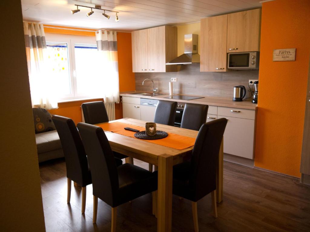 uma cozinha com uma mesa de madeira e cadeiras pretas em Ferienwohnung Bing em Rust