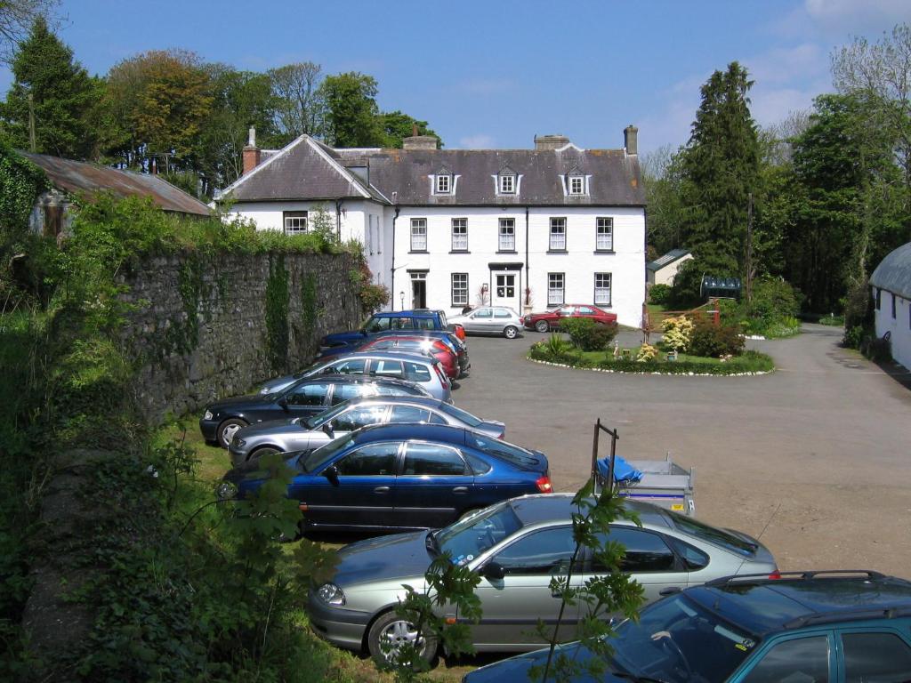 a row of cars parked in front of a white building at Priskilly Forest Country House in Fishguard