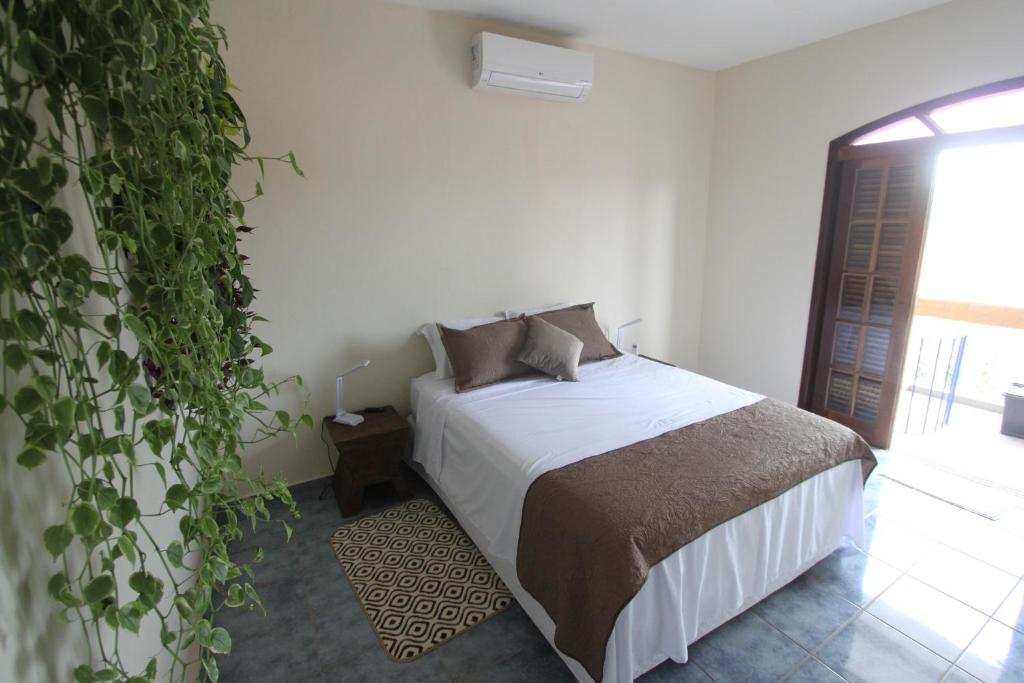 ein Schlafzimmer mit einem Bett und einer großen Pflanze in der Unterkunft Estação Brotense - Casa com piscina e fogueira exclusiva in Brotas