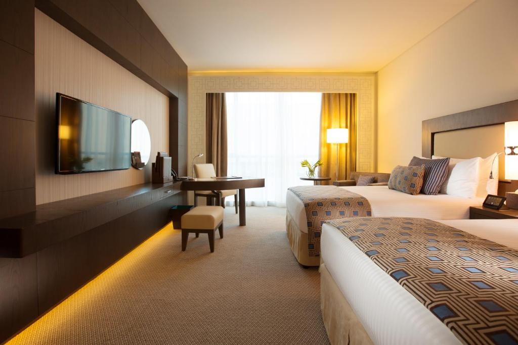 a hotel room with two beds and a desk at Royal M Hotel Fujairah by Gewan in Fujairah