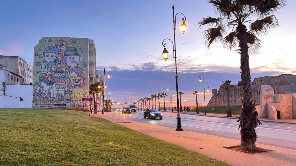 un coche conduciendo por una calle con un edificio con un mural en RABAT Appartement COSY CENTRE VILLE AU FRONT DE MER en Rabat