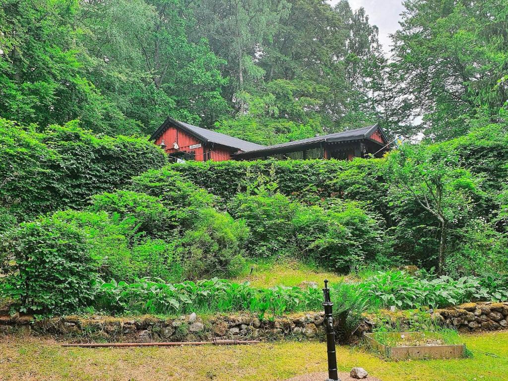 una casa roja en medio de un bosque en Holiday home TJÖRNARP VII en Tjörnarp