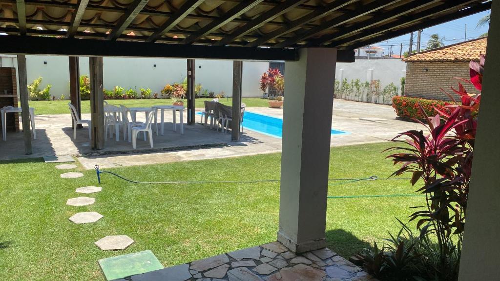 a patio with a table and chairs in a yard at Casa aconchegante com piscina e muito espaço verde in Aracaju