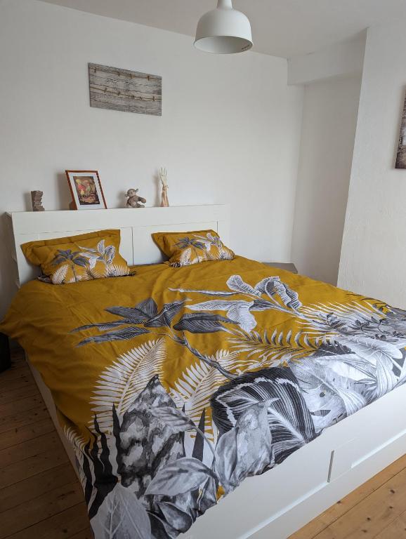a bedroom with a bed with a yellow and blue blanket at Maison de quartier populaire. in Aubusson