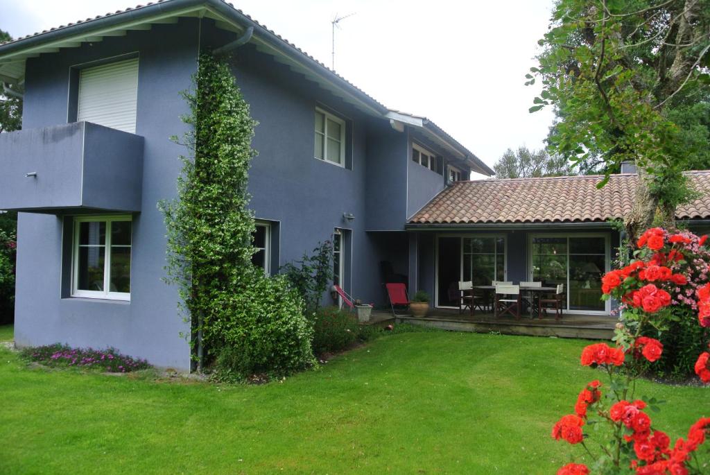 une maison bleue avec une cour ornée de fleurs rouges dans l'établissement Villa 8 personnes proche d'Hossegor au bord du Golf de Pinsolle, à Soustons