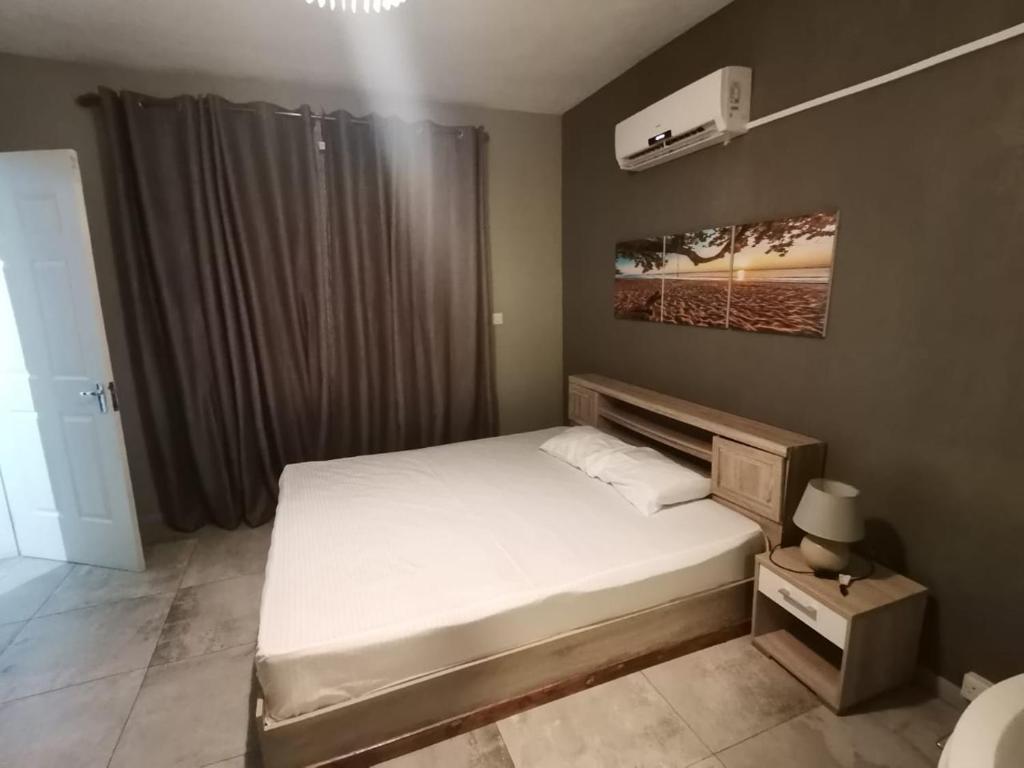 1 dormitorio con cama blanca y ventana en Residence YG, en Palmyre