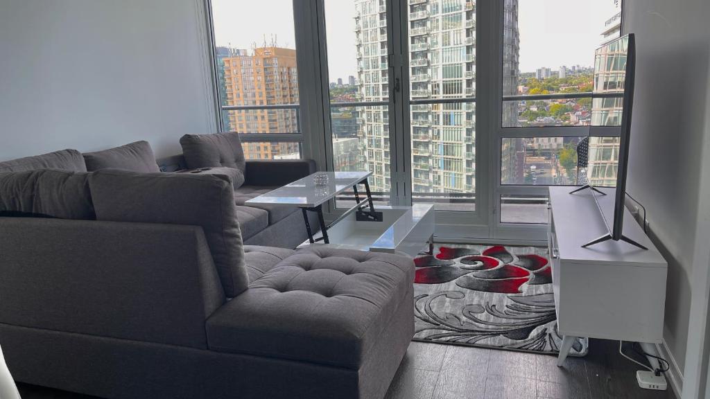 ein Wohnzimmer mit einem Sofa, einem Tisch und Fenstern in der Unterkunft Exquisite Condo By Exhibition Place Downtown Toronto in Toronto