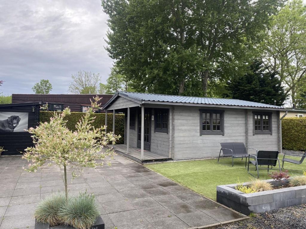 a small house with a patio in the yard at Atmospheric chalet with a spacious garden, in Friesland in Tzummarum