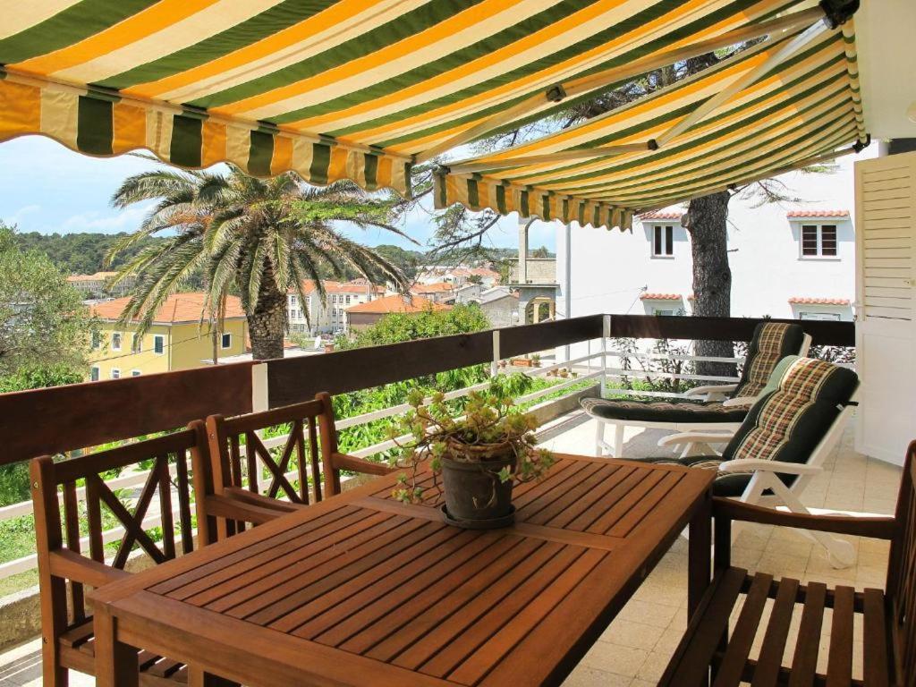 a wooden table and chairs on a balcony with a umbrella at Apartman Maria 1 in Rab