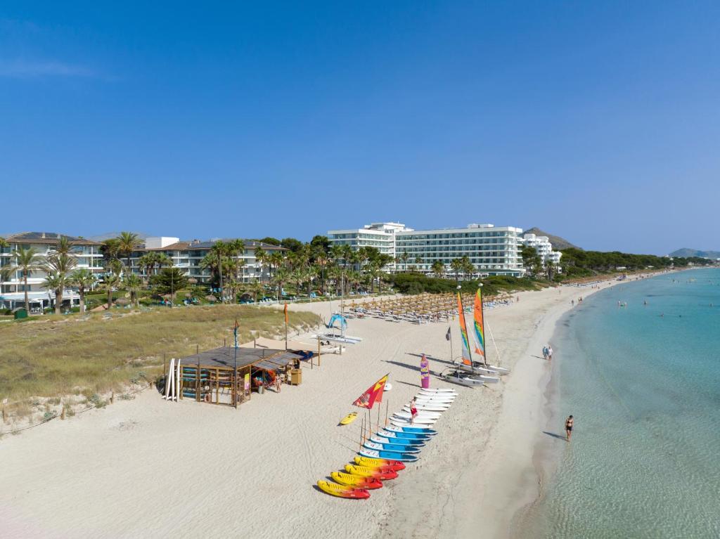 a beach with chairs and umbrellas and the ocean at Playa Esperanza Resort Affiliated by Meliá in Playa de Muro