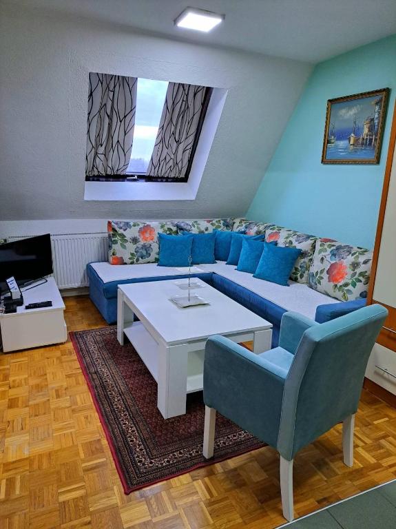 a living room with a blue couch and a table at A First class za 4 osobe 2 spavaće sobe in Tuzla