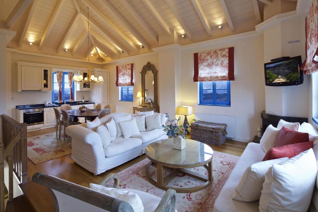 una sala de estar con sofás blancos y una mesa. en Zagori Suites Luxury Residences en Vítsa