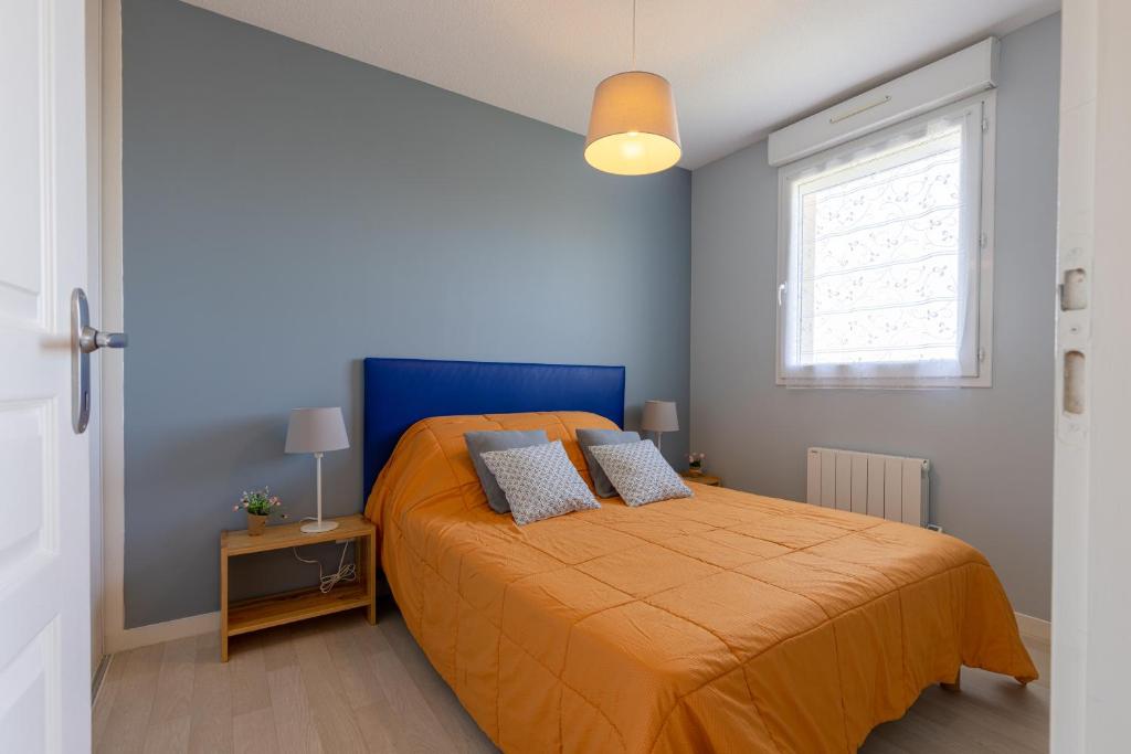 1 dormitorio con 1 cama con colcha de color naranja en LaConciergerieJonzac, Appartement Belles Des Champs, en Jonzac