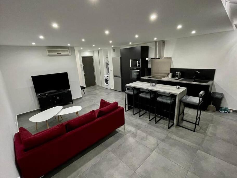 salon z czerwoną kanapą i kuchnią w obiekcie Appartement 3 pièces refait à neuf. Centre-ville. w Mentonie