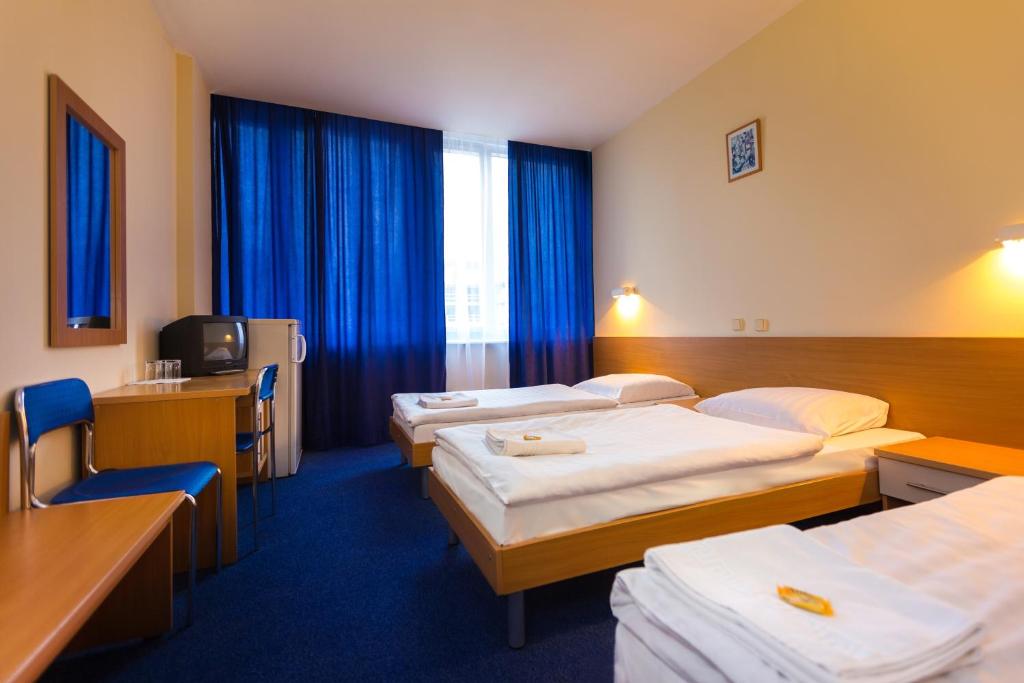 a hotel room with three beds and a television at Dom Turystyczny Indigo in Krakow