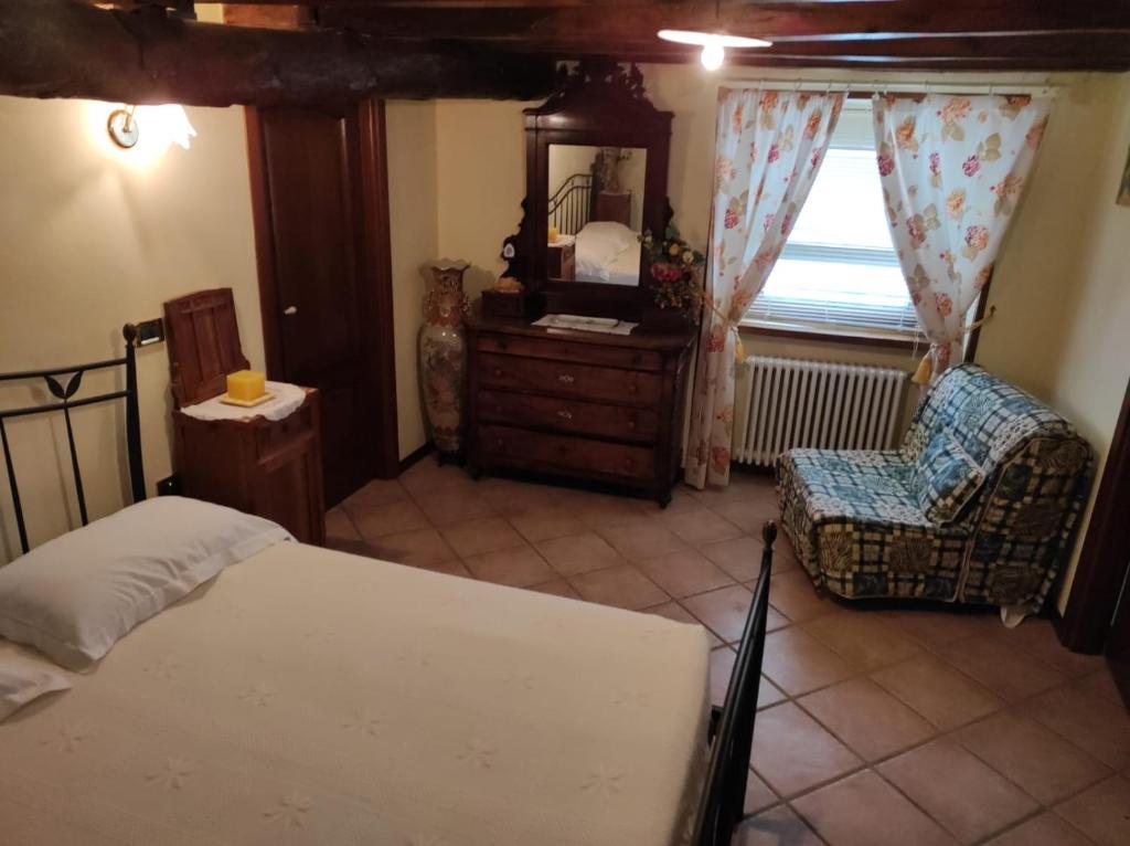 1 dormitorio con cama, silla y espejo en Agriturismo Alpi, en Roccaforte Ligure