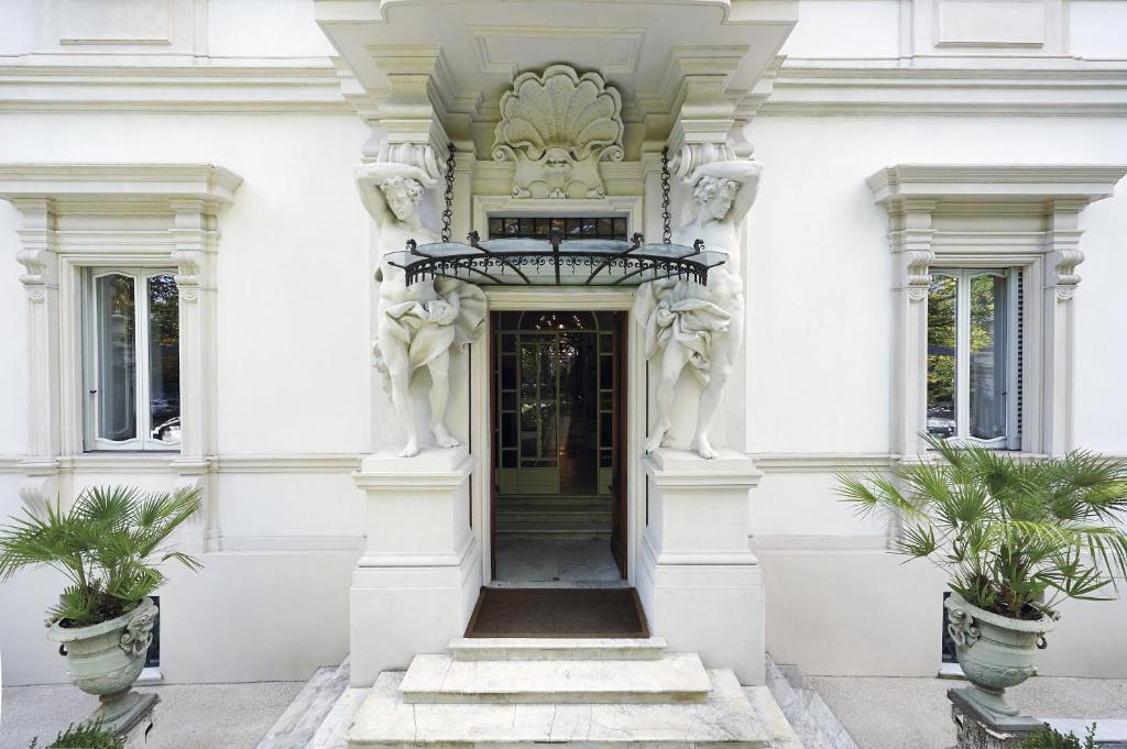 ein weißes Gebäude mit einer Tür mit zwei Pflanzen in der Unterkunft Villa Laetitia in Rom