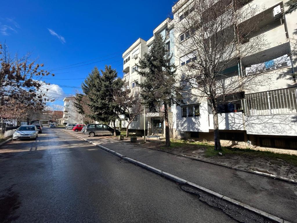 une rue vide avec des voitures garées sur le côté d'un bâtiment dans l'établissement Viktor apartment, à Kumanovo