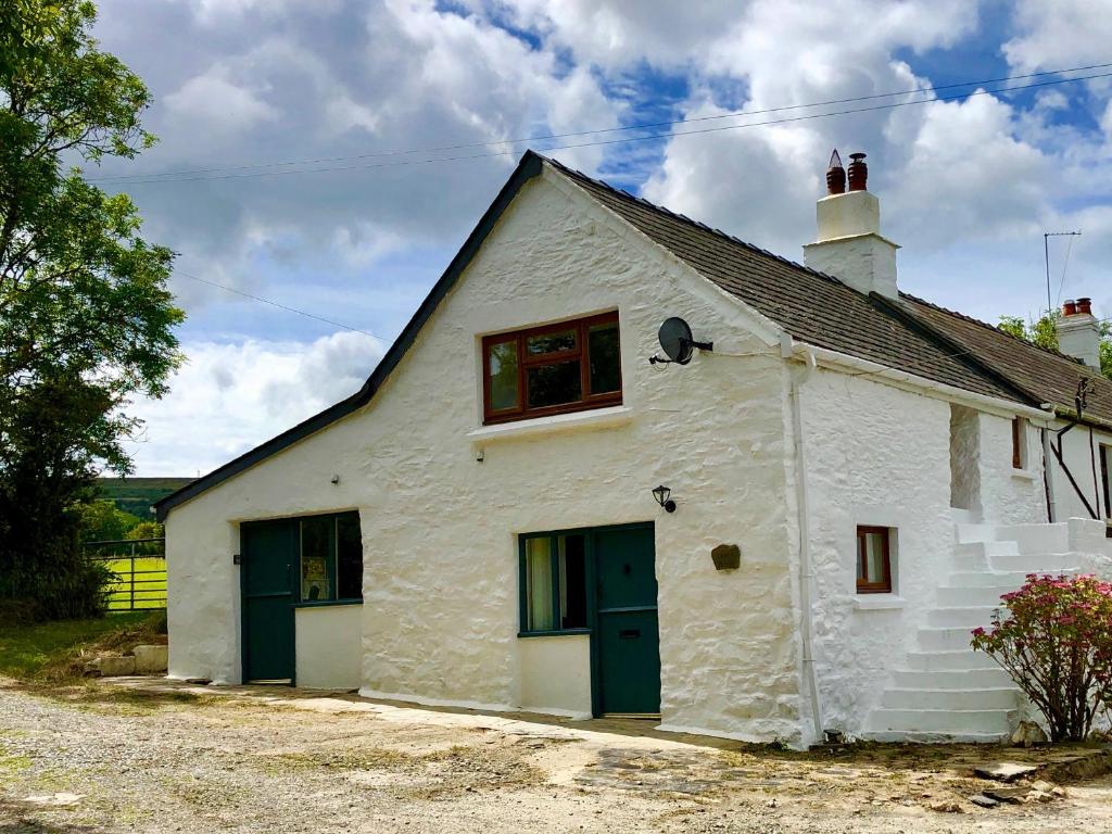 a white building with green doors and windows at Little Barn Cottage in Newport Pembrokeshire