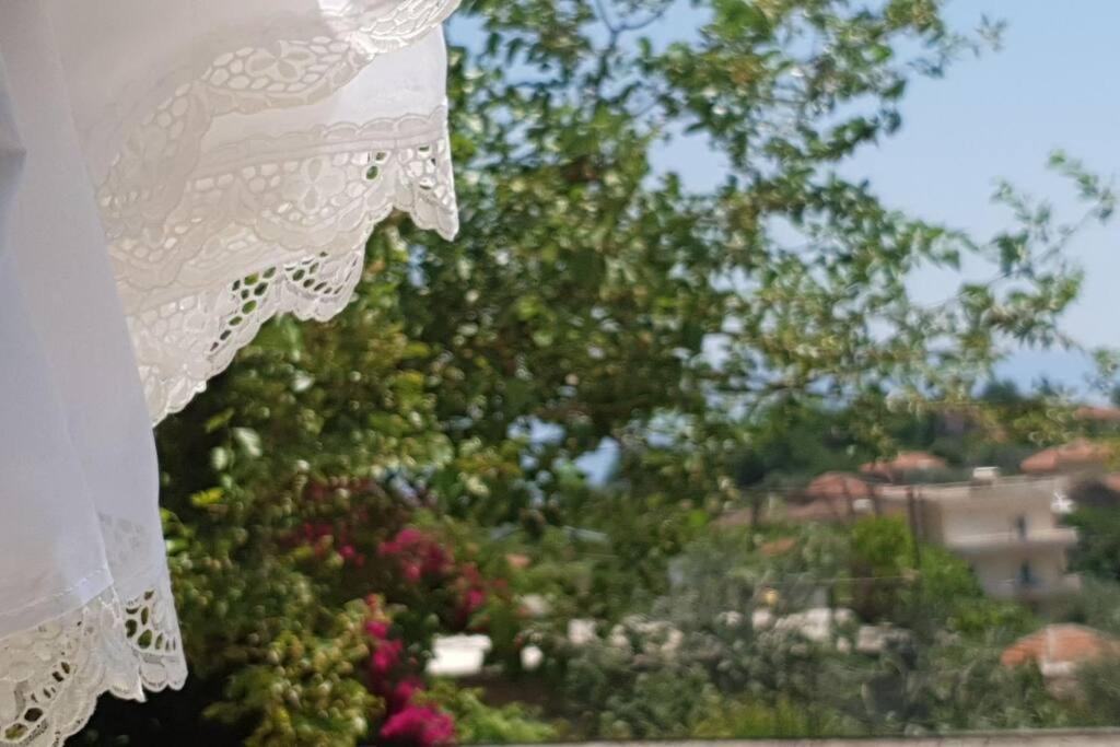 una ventana con vistas a un jardín con flores y árboles en Seaview Country House, en Sarandë