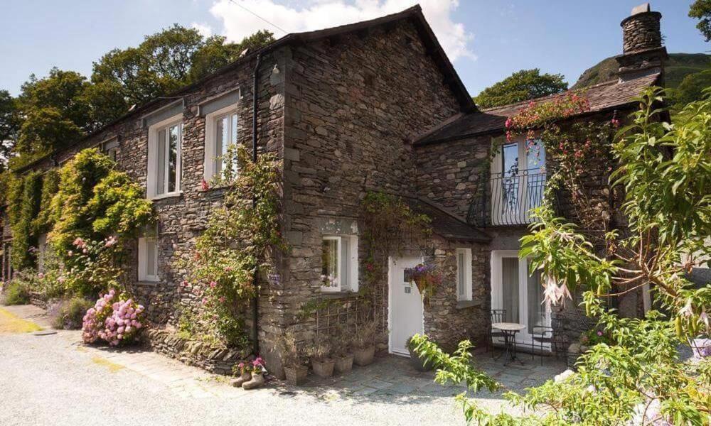 una vecchia casa di mattoni con edera che cresce sopra di Hart Head Barn ad Ambleside