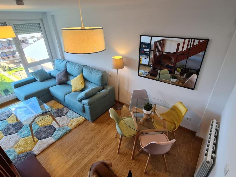 Nuevo apartamento de dos plantas في Renedo de Piélagos: غرفة معيشة مع أريكة زرقاء وطاولة زجاجية