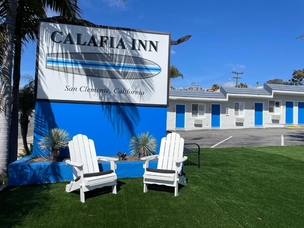 due sedie bianche sedute sull'erba di fronte a un cartello di Calafia Inn San Clemente Newly renovated a San Clemente