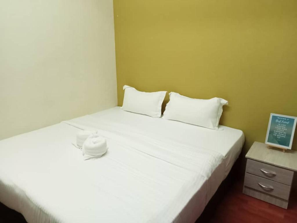 a bedroom with a bed with white sheets and a candle on it at Aeropod Hostel Economy Deluxe King Room in Kota Kinabalu