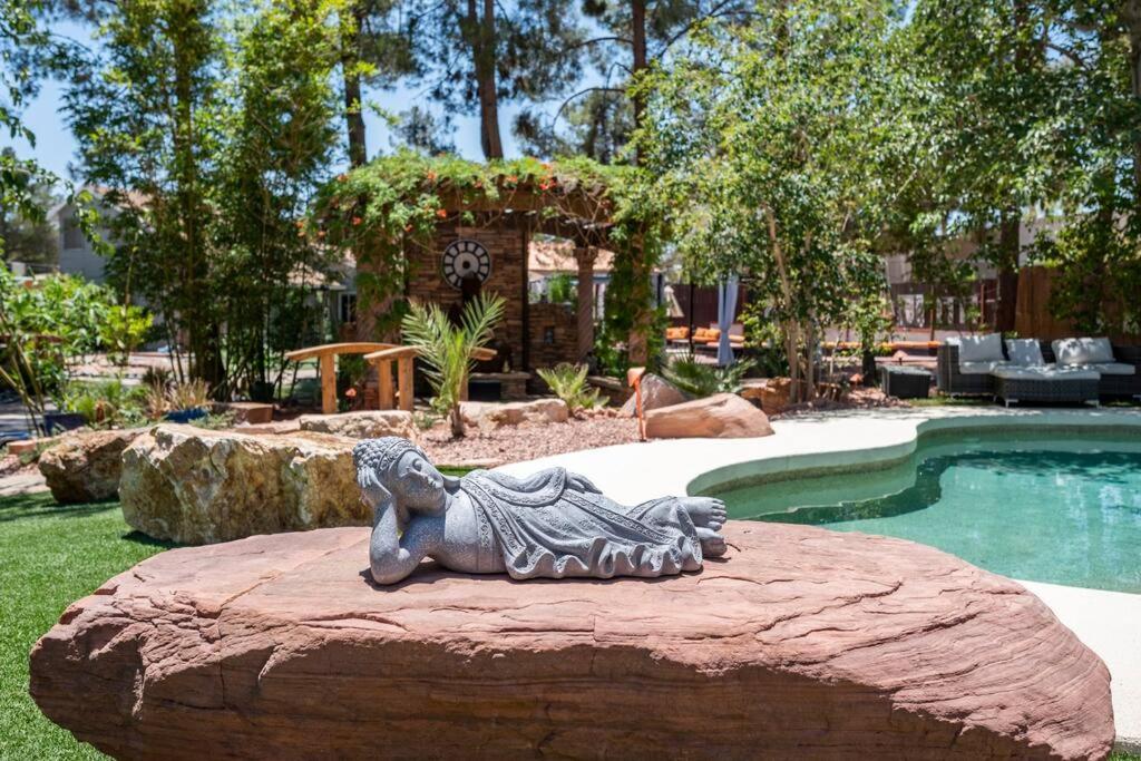 ラスベガスにあるResort-Style Paradise w 2 Poolsの池の横の岩に座る獅子像