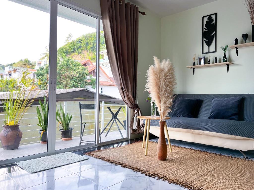 a living room with a blue couch and a large window at Panwa beachfront apartments in Ban Ao Makham