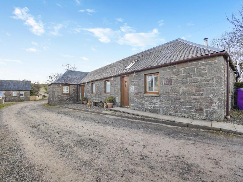 ein Steinhaus an der Seite einer unbefestigten Straße in der Unterkunft Appletree Cottage in Kirkton of Tealing