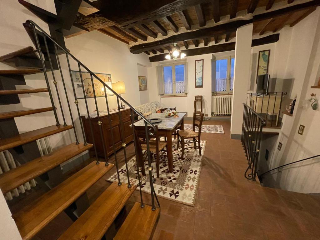 een woonkamer met een tafel, stoelen en een trap bij PULCINELLA appartamento tipico centro storico in Montepulciano