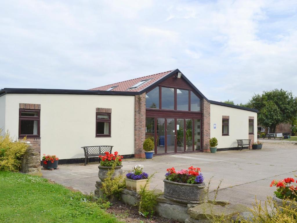 a white building with windows and flowers in a yard at Snowdrop Cottage - W43121 in Goxhill