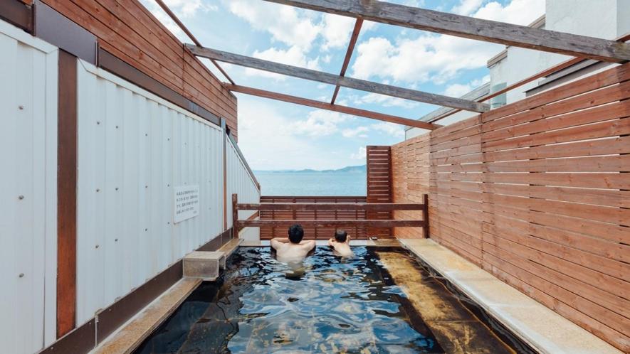 two people sitting in a koi pond in a building at Yunoko Umi To Yuyake in Minamata