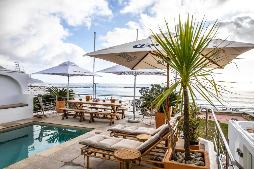eine Terrasse mit einem Tisch, Stühlen und einem Pool in der Unterkunft Primi Seacastle in Kapstadt