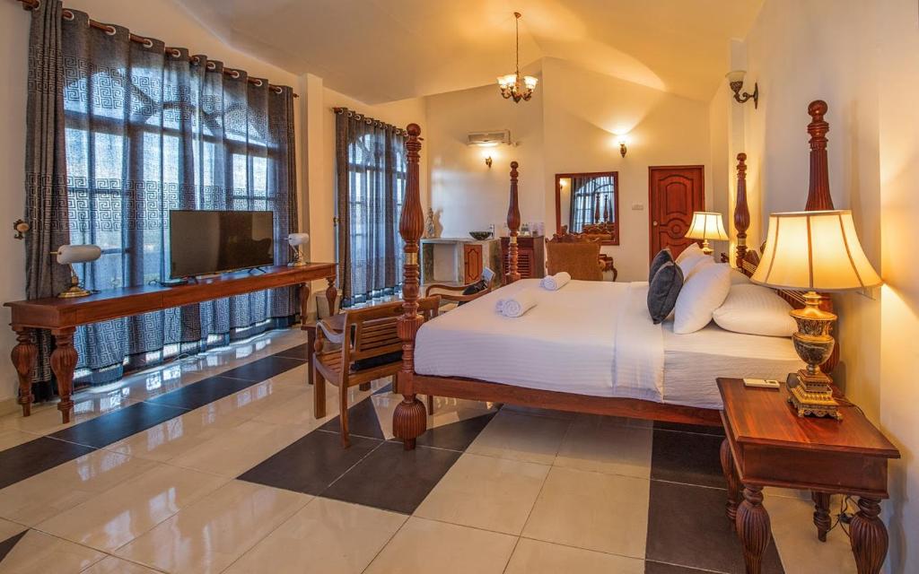 a bedroom with a large bed and a television at Ceylon Breeze in Kandy
