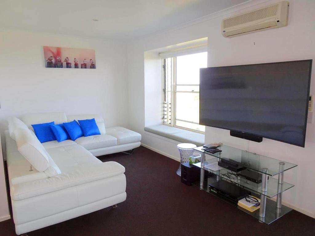 sala de estar con sofá blanco y TV de pantalla plana en Sea Views at Aqualuna 9 Solitary Islands Way 94, en Coffs Harbour