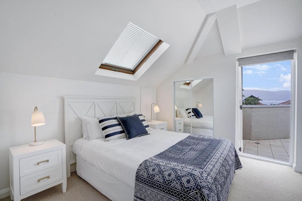a white bedroom with a bed and a window at The Lookout at Iluka Resort Apartments in Palm Beach