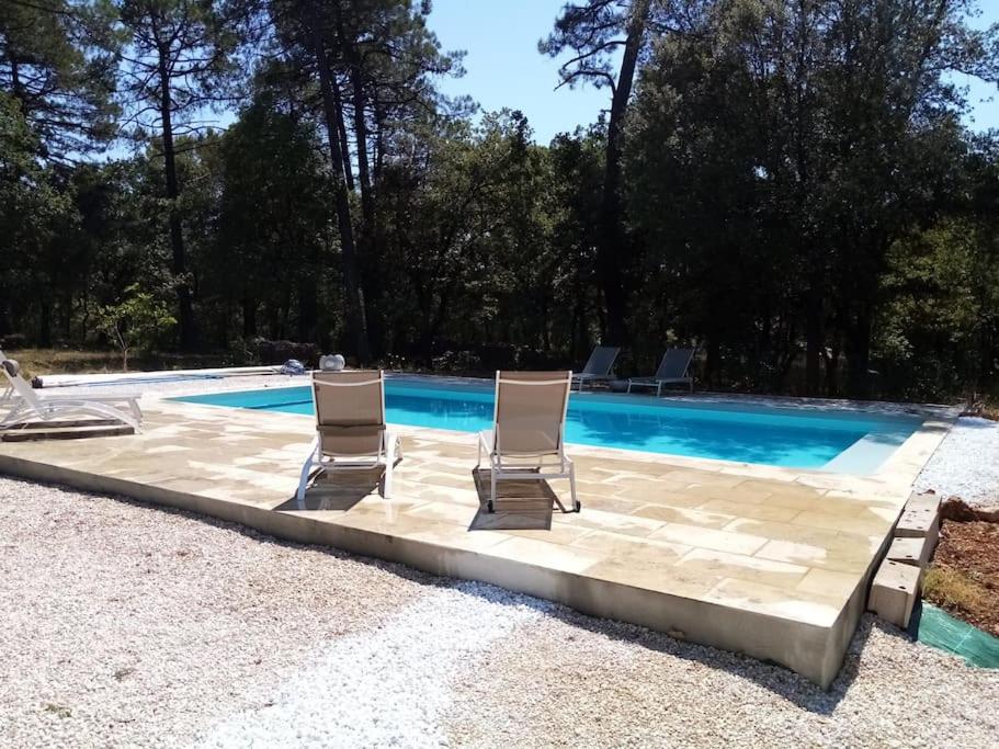 uma piscina com duas espreguiçadeiras e uma piscina em Provencale House + swimming poll in garden of 1HA em Besse-sur-Issole