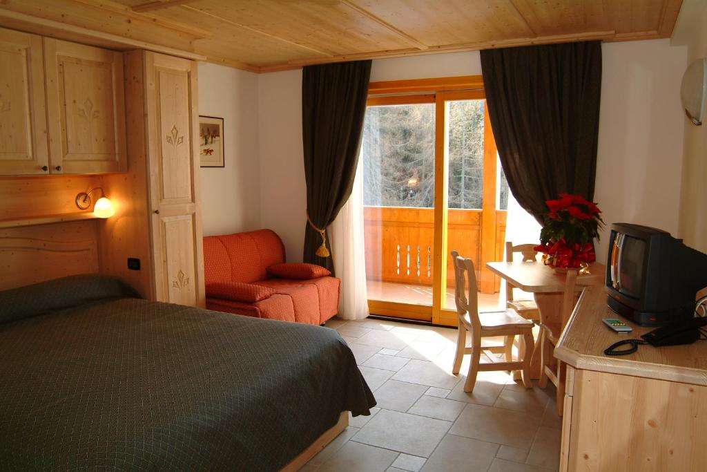 1 dormitorio con 1 cama y escritorio con TV en Boscone Suite Hotel, en Madesimo